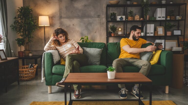 man and a woman are sitting on opposite ends of the sofa